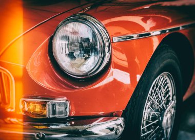 Kırmızı parlak klasik eski model araba önden görünümü. Retro tonda kartpostal, poster.