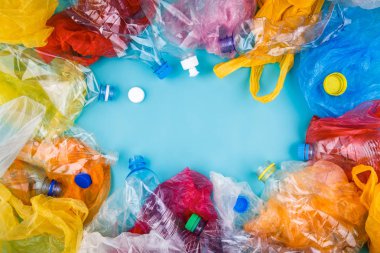 Çok renkli plastik şişeler, kapaklar, camgöbeği mavi zemin üzerine çanta. Kopyalama, metin, yazı için boş alanı. Plastik koleksiyonu poster afiş kavramı şablonu.