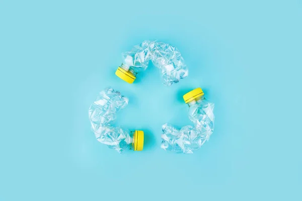 Три Розбиті Пластикові Пляшки Синьому Фоні Утворюють Знак Переробки Концепція — стокове фото