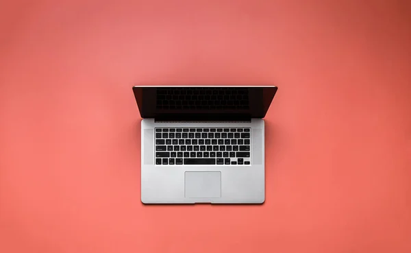 Laptop op lichtrode achtergrond bovenaanzicht — Stockfoto