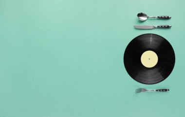 Soyut pastel arka planda plaka, bıçak ve çatal olarak plaka kaydı düz. Müzik zevki veya retro kafe yaratıcı, kopyalama alanı ile minimum konsept.