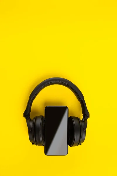 黑色无线耳机和智能手机在明亮的黄色彩色背景 带有复制空间的移动音乐应用创意最小概念 — 图库照片