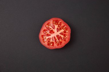 Yarım kesilmiş domatesin fotokopi alanı olan soyut siyah arkaplan görüntüsü. Koyu sebze konsepti.