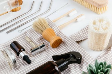 Çevre dostu banyo ve mutfak aksesuarları sade beyaz masa arkasına yerleştirilmiş. Sürdürülebilir yaratıcı yaşam tarzı konsepti. Basit bileşim izometrik görünümünü temizle.