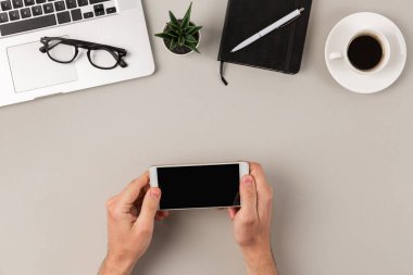 Gri modern ofis masasında peyzaj yönetiminde beyaz akıllı telefon kullanan erkek eller. Uzayı kopyala Video konsepti izlemek.