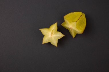 Soyut siyah arkaplanda izole edilmiş, kopyalama alanı olan karabol meyvelerini kes. Koyu egzotik meyve kavramı.