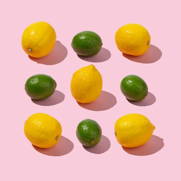 Limes and lemons arrangement on pastel pink background. Creative summer isometric concept.