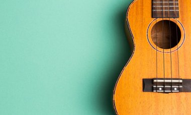 Ukulele 'nin fotokopi alanı olan soyut turkuaz arka planda yakın plan görüntüsü. Yaratıcı düz konsept.