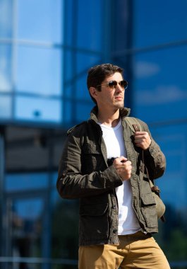 Güneş gözlüklü ve ceketli, kendine güvenen yakışıklı erkek portresi başka tarafa bakıyor. Metin için yer.