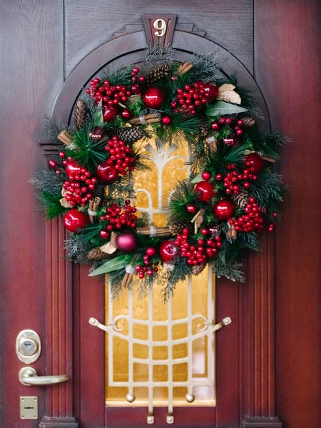 Porta de madeira é decorada para o Natal com uma grinalda sempre verde — Fotografia de Stock