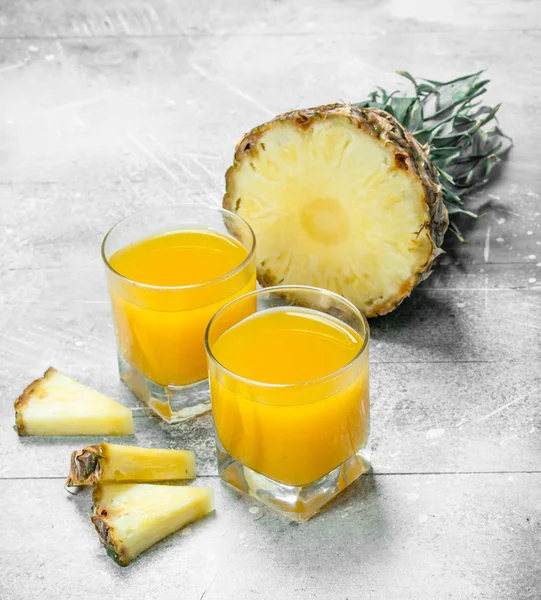 Pineapple juice in a glass and slices of ripe pineapple.