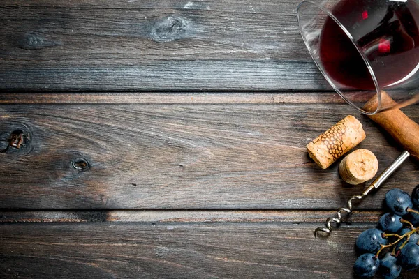 Wine background. A glass of red wine with a corkscrew and a vine.