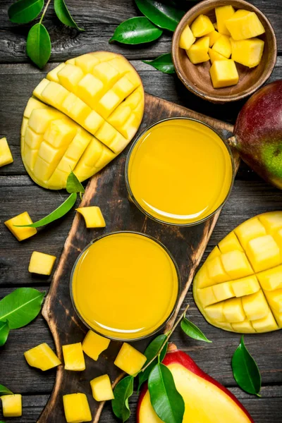 Mango juice and slices of fresh mango on the cutting Board.
