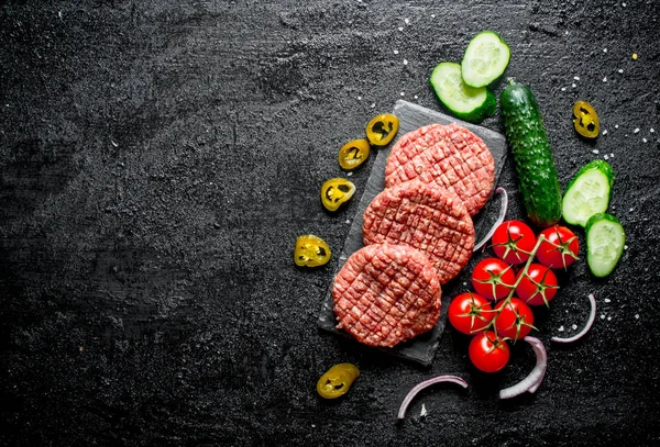 Raw burgers with jalapeno chillies, tomatoes and cucumbers.