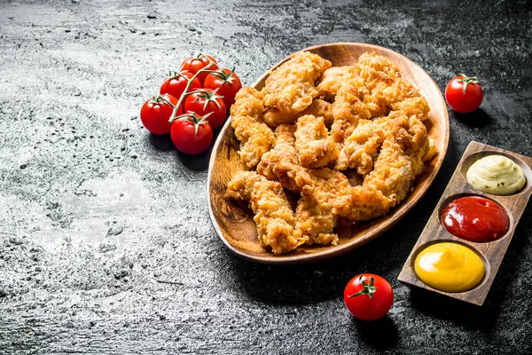 Chicken strips with cherry tomatoes and various sauces.