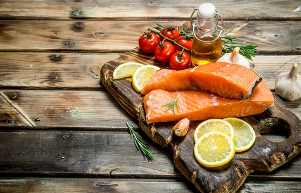 Raw salmon fish filet with lemon, tomatoes and herbs.