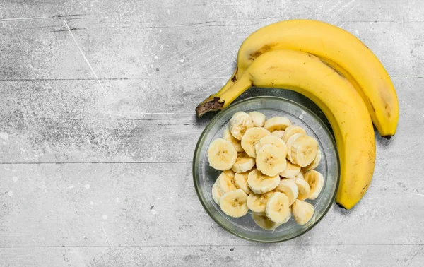 Bananas and banana slices in a glass plate.