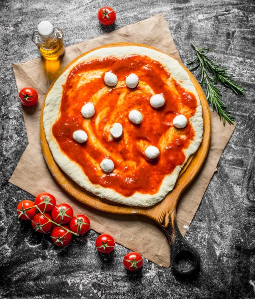 Raw pizza. Rolled out dough with mozzarella and tomato paste.