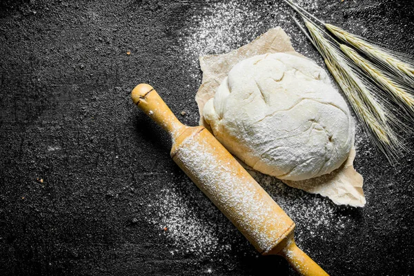 The dough on the paper with the ears and with a rolling pin.