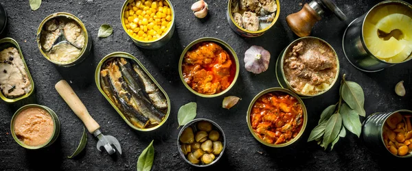 Canned food in various open cans with garlic cloves and Bay leaf.