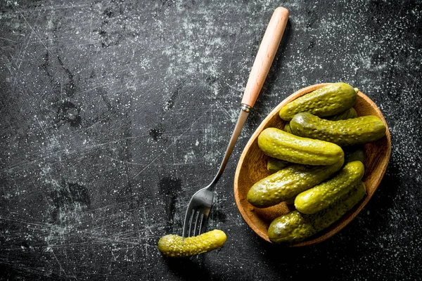 Preserved cucumbers on a plate with one cucumber on a fork.