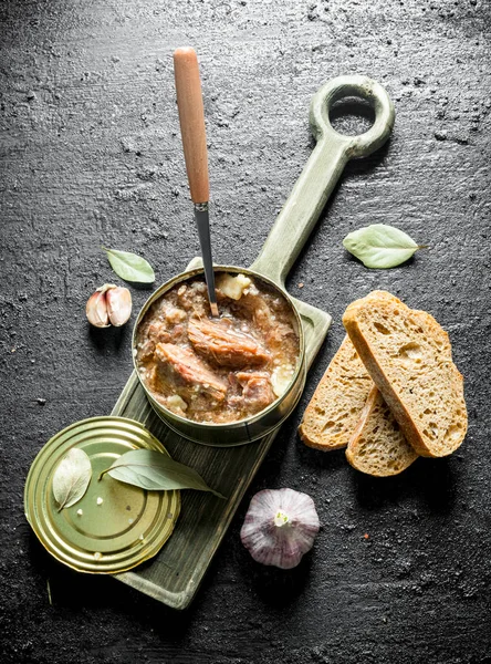 Open can of canned meat on a cutting Board.