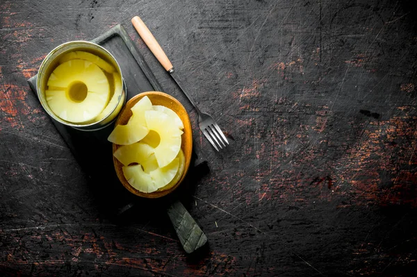 Canned pineapples in a tin can and on a plate.