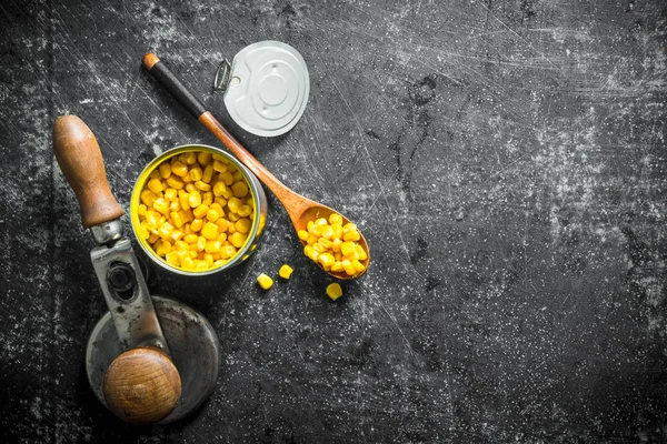 Canned corn in a tin can and a spoon.