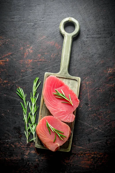 Fresh raw tuna steak on a cutting Board with rosemary.