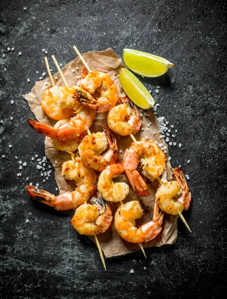 Grilled shrimps on paper with the cut lime.