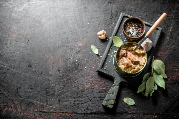 Canned meat in a tin on a cutting Board.