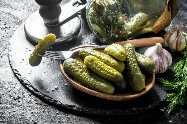 Preserved cucumbers on a plate with one cucumber on a fork.
