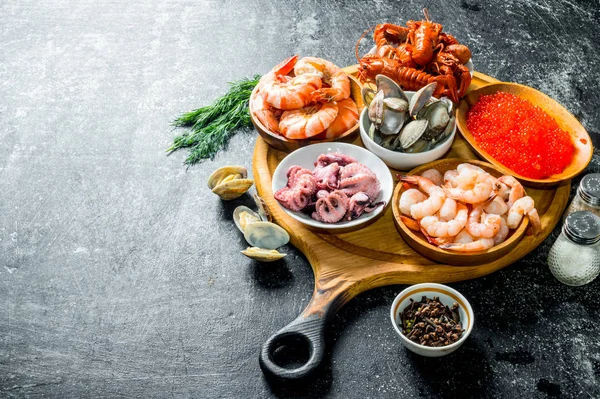 Seafood. Shrimp, crayfish, oysters, octopus and caviar in bowls on the chopping Board.