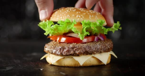Mužská ruka položí na hamburger buchtu.. 