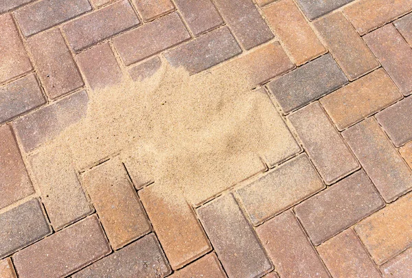Brushing kiln dried sand in to block paving