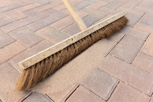 Brushing kiln dried sand in to block paving