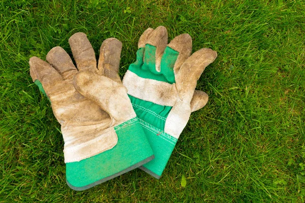 Used gardeners gloves on a green grass background