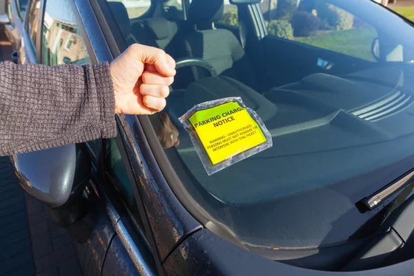 Man shaking his fist at being given a parking ticket