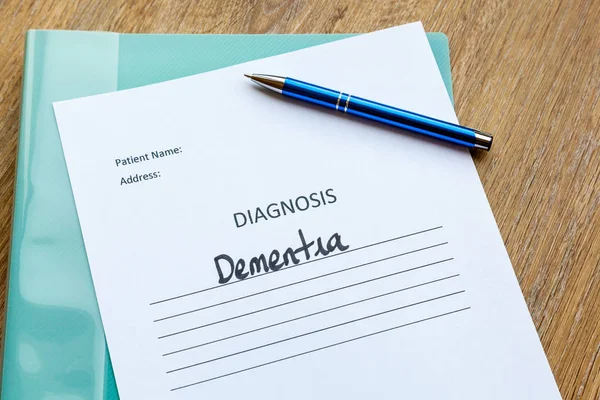 Dementia diagnosis written on paper with a folder and pen.
