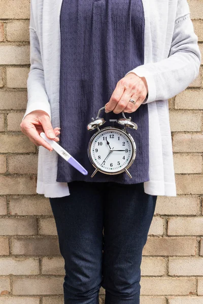 Woman, clock and negative pregnancy test - biological clock concept