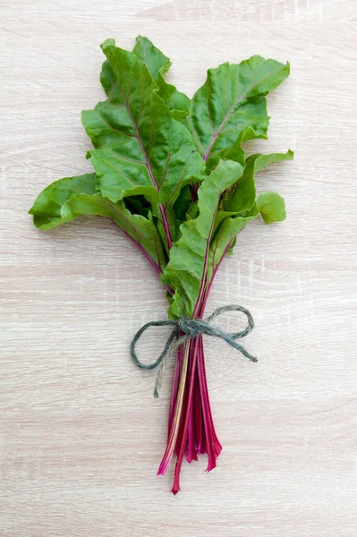 Bunch of beetroot leaves and stems on a light wood background