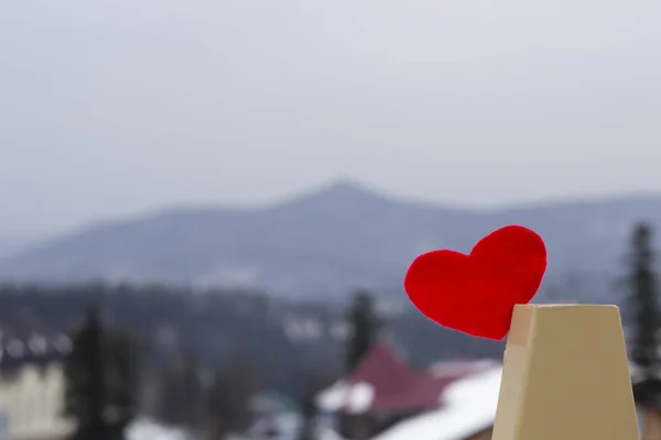 Red felt heart on the winter mountains ski resort background. Love winter, sport concept. Copy space