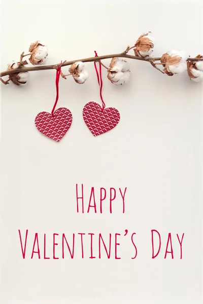 Cotton branch and two red paper hearts with text Valentine\'s Day