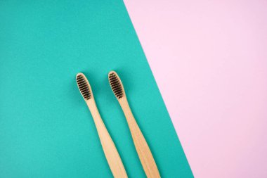 Turkuaz pembe arka planda iki bambu diş fırçası. Aşk, sağlık, sıfır atık, tedavi konsepti. Üst görünüm, düz görünüm, kopyalama alanı