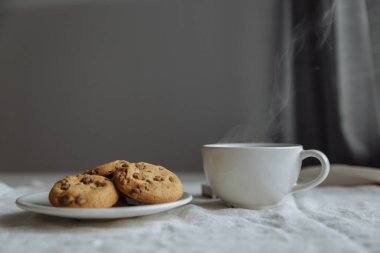 Kahverengi kurabiyeler beyaz tabakta ve kahve beyaz bardakta