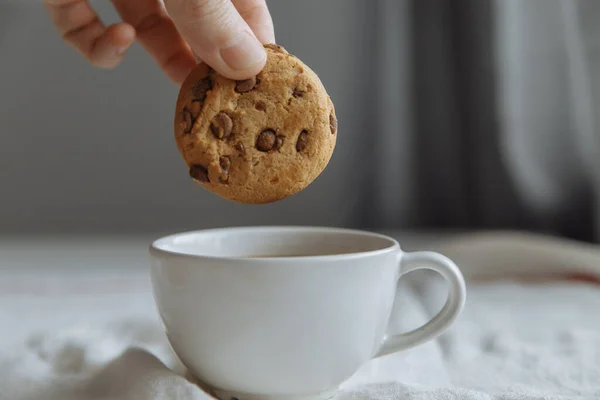 Hand wants to dip brown cookies in a glass with coffee. — Stock Photo, Image