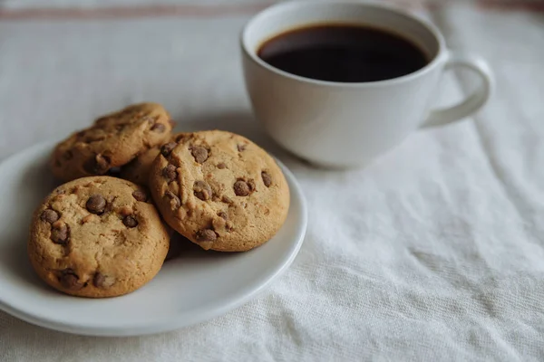 Galletas marrones en el plato blanco y café en vidrio blanco —  Fotos de Stock