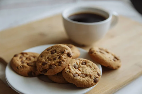 Galletas marrones en el plato blanco y café en vidrio blanco — Foto de Stock