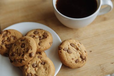 Kahverengi kurabiyeler beyaz tabakta ve kahve beyaz bardakta