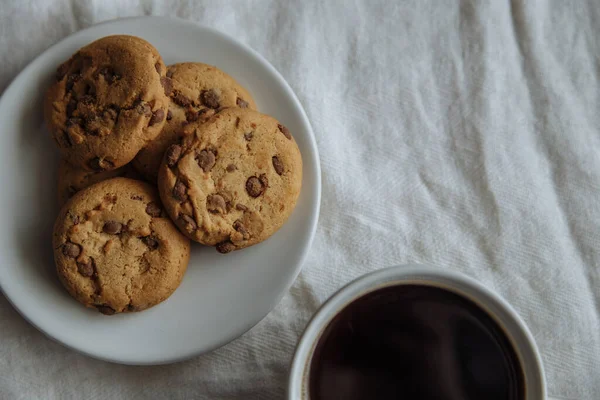 Brown cookies on the white plate and coffee in white glass — Stock Photo, Image